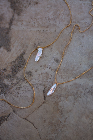 Two Elara pearl necklaces on a sandstone surface