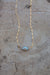 Diamond shaped pearl strung between two lengths of dapped gold chain