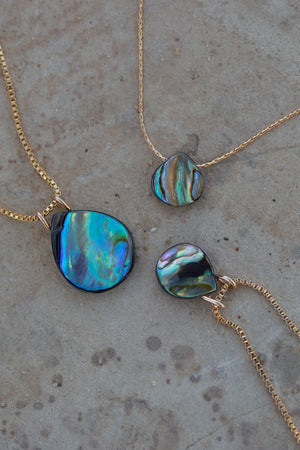 Detailed view of the abalone pendants of varying sizes with and without a gold bail.