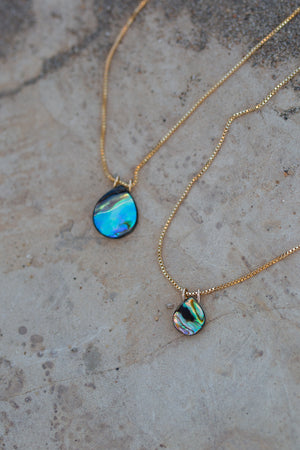 Close up view of venetian gold chain with abalone pendants in large and small sizes. Abalone pendants are iridescent blue and green rainbow swirls.