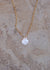 Close up of gold necklace with pearlescent mother of pearl scallop shell