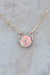 An up close view of the mother of pearl coin pendant, strung with a gold sliding bail on a dainty gold cable chain