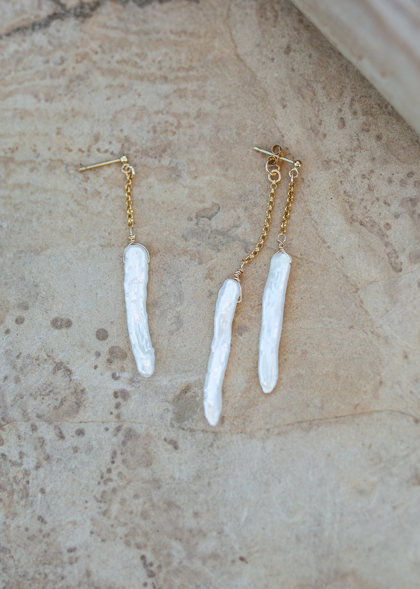 Gold post earrings with long white stick pearls hanging from chains