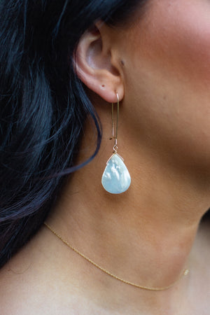 Detailed look at mother of pearl droplet earrings on model