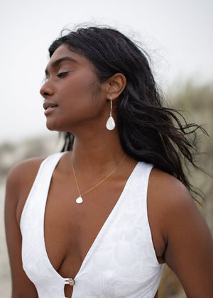 Thetis earrings on model wearing matching necklace and white swimsuit